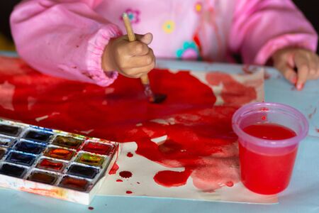 child paints with brush and colorful paints on paperの写真素材
