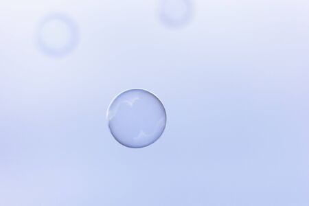 One soap bubble in the middle of the shot on blue backgroundの写真素材