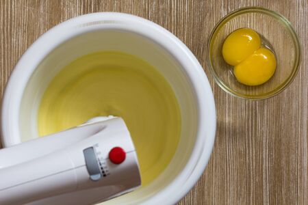 Egg yolks are whisked with sugar in the mixer bowlの写真素材