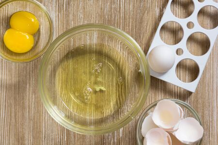 Separated raw chicken yolk and whites on the wooden tableの写真素材