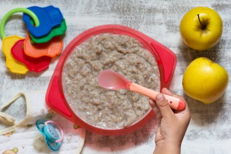 Top view of hand of child holding the spoon to eat milk buckwheat porridgeの写真素材