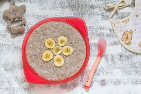 Top view of milk buckwheat porridge with banana as decoration for child on the white backgroundの写真素材
