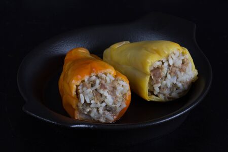 Stuffed pepper with rice and meat on black plate on the black backgroundの写真素材