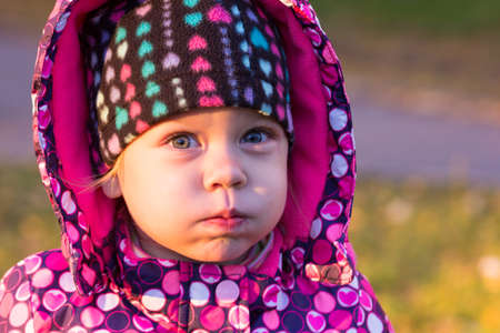 Portrait of little girl puffing out cheeks outdoorsの写真素材