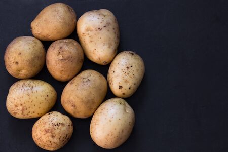 top view of heap of unpeeled raw potato on the black background