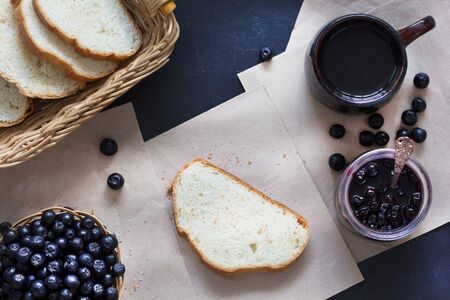 Top view of chokeberry jam in the jar, chokeberries, loaf, cup of teaの写真素材