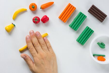 Woman hand rolling sausage from polymer clay on the white backgroundの写真素材