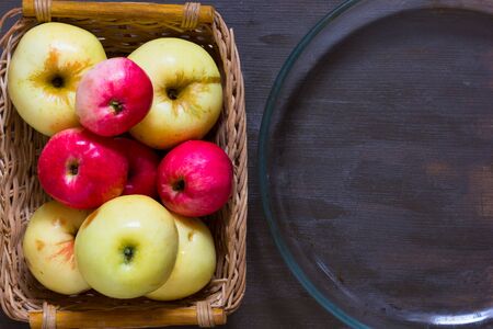 Apples and empty glass dish for baking on the wooden background