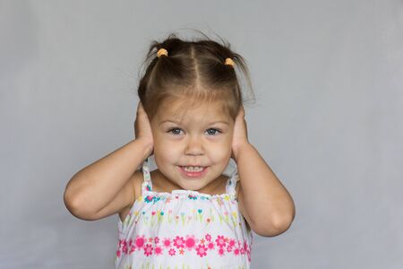 Smiling child does not want to hear anything closing her ears by handsの写真素材