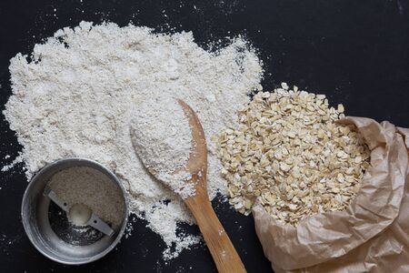 Top view of oats and the coffee grinder for making oat flour on black backgroundの写真素材