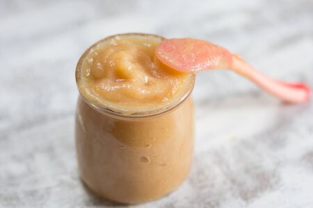 Apple sauce in glass jar and spoon on the white backgroundの写真素材