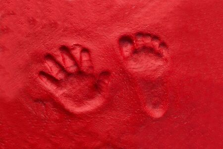 Hand and foot print of child made on red backgroundの写真素材