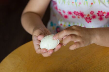 Hand of child peeling cooked egg pulling off shellの写真素材