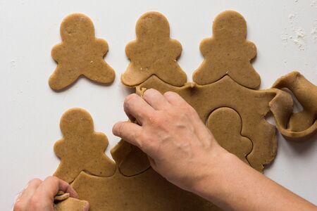 Excess of gingerbread dough removing from rolled out and cutted dough by woman hand on the white backgroundの写真素材