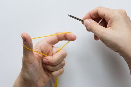 Casting on. Knitting. Position of fingers and thread for stitches on the white background. Top view.