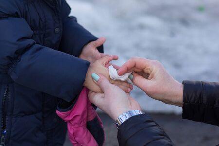 Woman hands wipe with napkin child hands in winter parkの写真素材