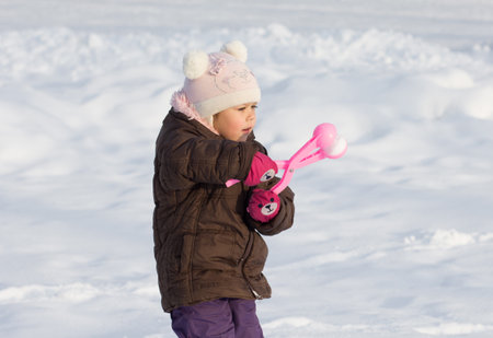 Caucasian child of three years old making snowballs with special toy in winter parkの写真素材