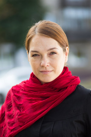 Portrait of caucasian middle aged woman looking at camera with soft look and smile outdoor