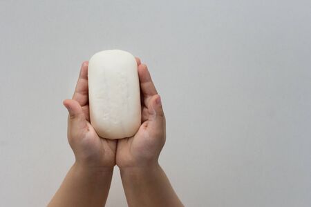 Top view of child hands holding soap before washing hands on white backgroundの写真素材