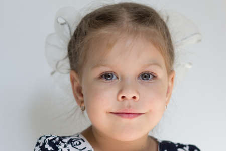 Portrait of smiling caucasian child of three years old with two big bows on head on white background