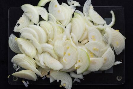 Top view of cutted in half lengthwise onion strips on the black backgroundの写真素材