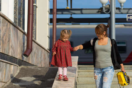 Caucasian child of two years old walking down holding mother hand supporting womanの写真素材
