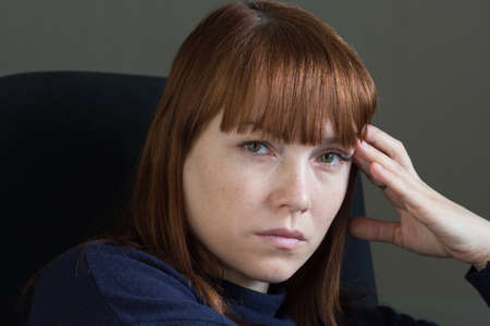 Portrait of middle aged woman with sad and unhappy look holding hand close to head and looking at...