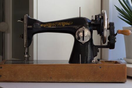 Old manual sewing machine with machine pulley and wooden handle