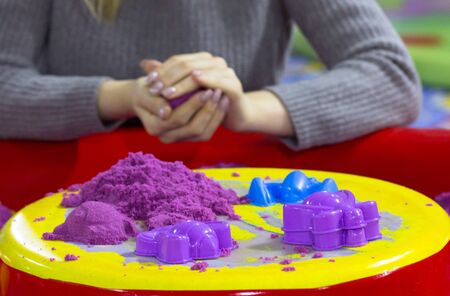 View of purple kinetic sand and forms for modeling on woman hands molding ball backgroundの写真素材