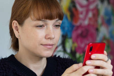 Portrait of cute smiling middle aged woman looking at mobile phoneの写真素材