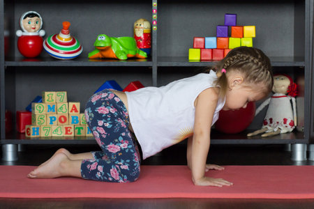 Little girl making yoga cat or cow pose arching back and opening chestの写真素材