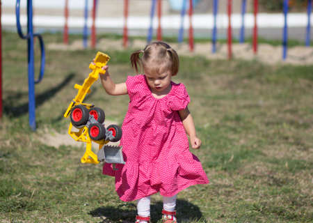 Caucasian little girl of two years old playing with toy car on playgroundの写真素材