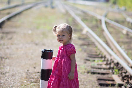 Caucasian little girl among rails on rail road in summertimeの写真素材