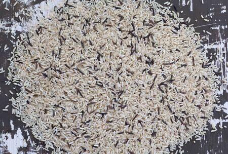 Top view of heap of raw mixed brown and black rice on the wooden backgroundの写真素材