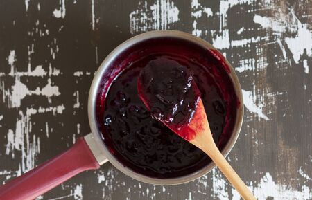 Top view of saucepan with cooked jam in it on the wooden backgroundの写真素材