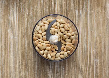 Top view of fried peanuts in kitchen processor to make homemade peanut butter on the wooden backgroundの写真素材