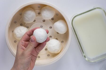 Top view of woman hand holding fresh homemade mozzarella ball and whey to store cheeseの写真素材