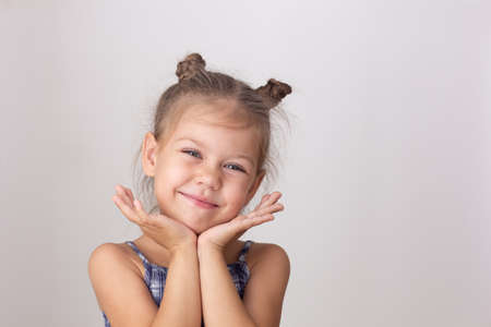 Portrait of caucasian cute little girl of five years old holdings head chin on hands on the white...