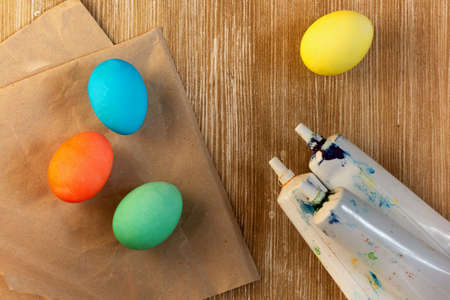 Top view of blue, red, green and yellow eggs after coloring on wooden background and food coloring tubesの写真素材