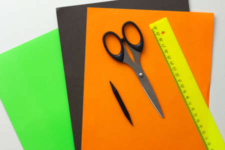 Top view of green, black and orange paper for diy and scissors, pencil and ruler on the white backgroundの写真素材