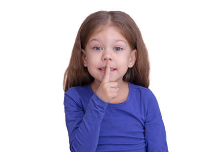 Child kid holding finger on mouth making tss shh asking silence and quiet, isolated on white background looking at camera waist up caucasian little girl of 5 years in blueの写真素材