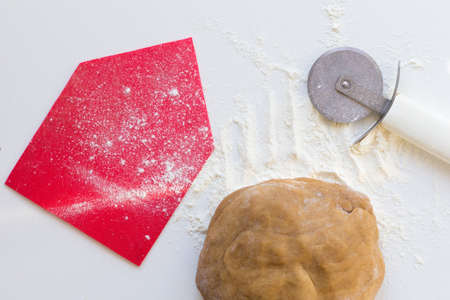 Homemade form for gingerbread house, ball of raw gingerbread dough and knife for cutting on white backgroundの写真素材