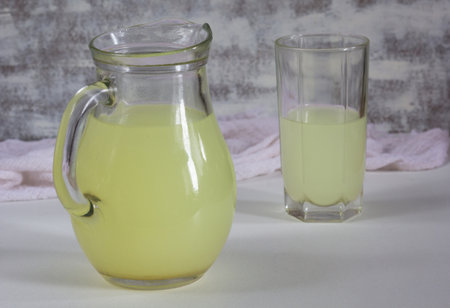 Jar and glass with liquid whey that remains after formation of curds on the white backgroundの写真素材