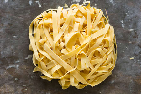 Heap of raw urved stripes of noodles on the wooden backgroundの写真素材