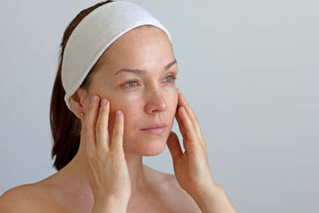 Middle aged woman without make up touching her faceの写真素材