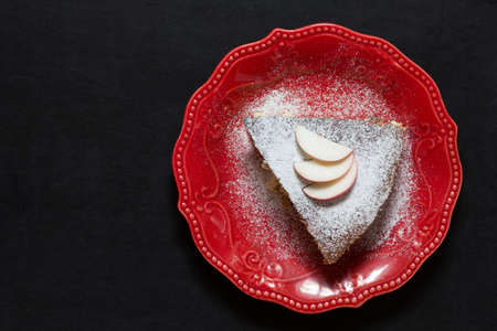 Top view of piece of apple cake on red plate on black backgroundの写真素材