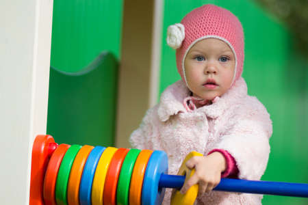 Little girl playing with the wooden toy counter outsideの写真素材