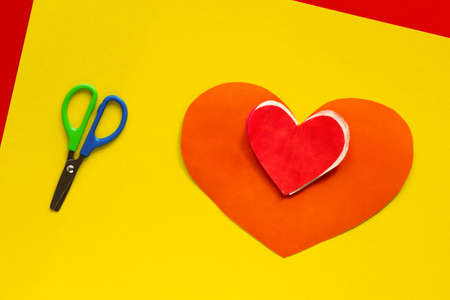 Top view of papercraft red heart and scissors on yellow backgroundの写真素材