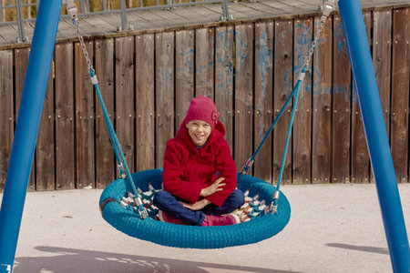 Smiling child of 8 9 years swinging on round seesaw looking at camera