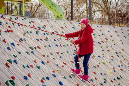 Happy child climbing on artificial rock wall using rope on playgroundの写真素材
